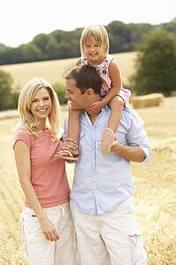 Family Walking Together Through Summer Harvested Field