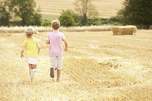 Children Running Through Summer Harvested Field
