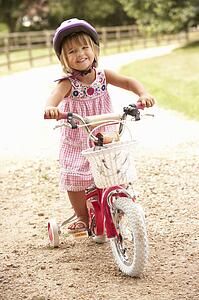 Girl Learning To Ride Bike Wearing Safety Helmet