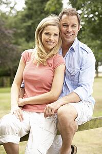Couple Relaxing In Countryside Sitting On Fence