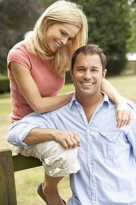 Couple Relaxing In Countryside Sitting On Fence