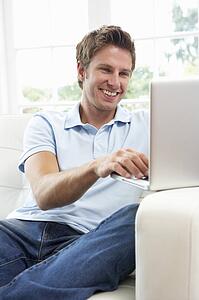 Man Sitting On Sofa Using Laptop At Home