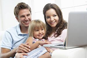 Family Sitting On Sofa Using Laptop At Home