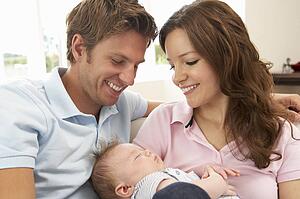 Close Up Of Parents Cuddling Newborn Baby Boy At Home