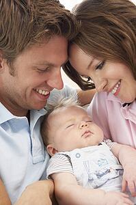 Close Up Of Parents Cuddling Newborn Baby Boy At Home