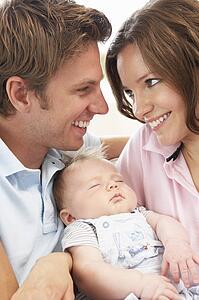 Close Up Of Parents Cuddling Newborn Baby Boy At Home