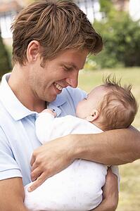 Close Up Of Father Cuddling Newborn Baby Boy Outdoors At Home