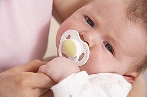 Close Up Of Baby Boy With Dummy Holding Mothers Hand