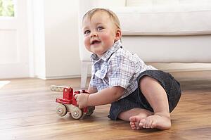 Young Boy Playing With Wooden Toy Car At Home