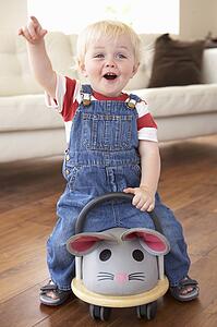 Young Boy Playing With Ride On Toy Mouse At Home