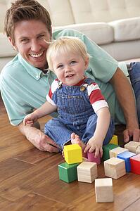 Father And Son Playing With Coloured Blocks At Home