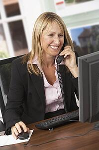 Female Estate Agent Talking On Phone At Desk