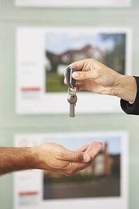 Close Up Of Estate Handing Over Keys Of New Home To Client
