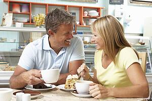 Couple Enjoying Slice Of Cake And Coffee In Café 