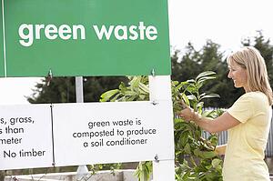 Man At Recycling Centre Disposing Of Garden Waste