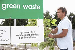 Woman At Recycling Centre Disposing Of Clothing