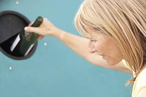 Woman At Recycling Centre Disposing Of Glass At Bottle Bank