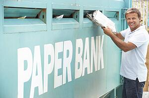 Man At Recycling Centre Disposing Of Old Newspapers