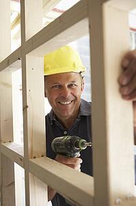 Construction Worker Building Timber Frame In New Home