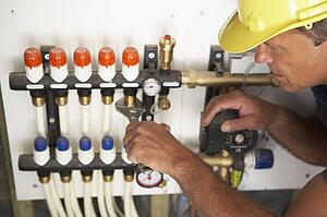 Plumber Working On Pipework In New Home