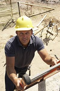 Construction Worker Climbing Ladder On Building Site For New Home