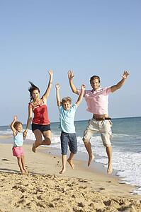 Portrait Of Family On Beach Holiday Jumping In Air