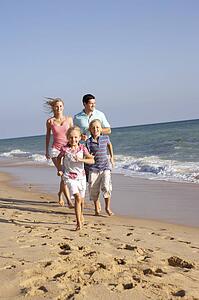 Portrait Of Running Family On Beach Holiday 