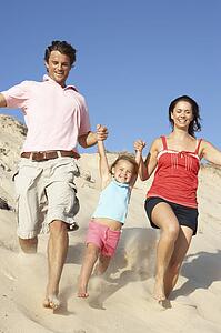 Family Enjoying Beach Holiday Running Down Dune