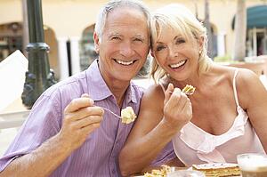 Senior Couple Enjoying Coffee And Cake In Café