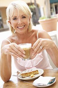 Senior Woman Enjoying Coffee And Cake In Café