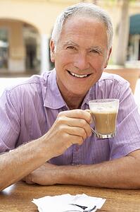 Senior Man Enjoying Coffee And Cake In Café