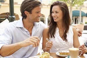 Young Couple Enjoying Coffee And Cake In Café