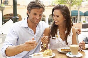 Young Couple Enjoying Coffee And Cake In Café