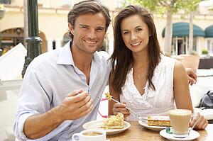 Young Couple Enjoying Coffee And Cake In Café