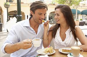 Young Couple Enjoying Coffee And Cake In Café