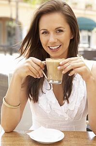 Young Woman Enjoying Cup Of Coffee In Café