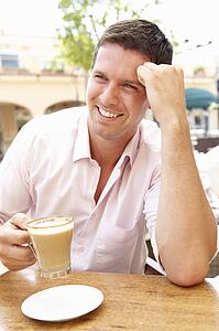 Young Man Enjoying Cup Of Coffee In Café