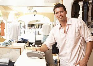 Male Sales Assistant At Checkout Of Clothing Store
