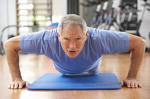 Senior Man Doing Press Ups In Gym