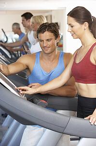 Woman Working With Personal Trainer On Running Machine In Gym