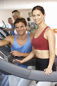 Woman Working With Personal Trainer On Running Machine In Gym