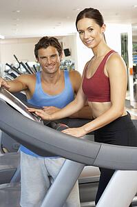 Woman Working With Personal Trainer On Running Machine In Gym