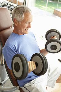 Senior Man Working With Weights In Gym