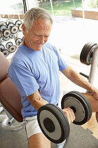 Senior Man Working With Weights In Gym