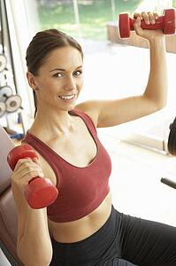Young Woman Working With Weights In Gym