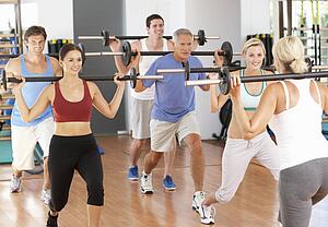 Group Of People Lifting Weights In Gym