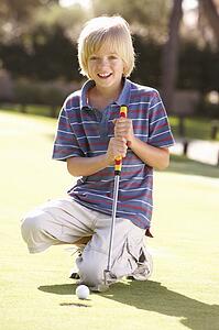 Young Boy Practising Golf On Putting On Green