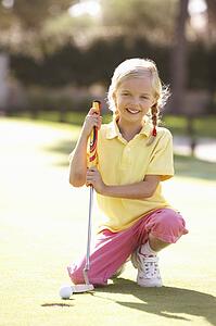 Young Girl Practising Golf On Putting On Green