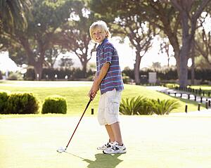 Young Boy Practising Golf On Putting On Green