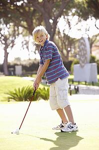 Young Boy Practising Golf On Putting On Green